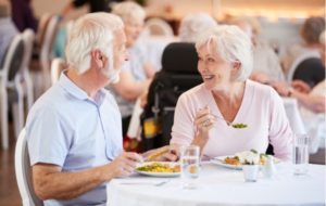 Two seniors enjoying dinner in the dining room at their retirement community