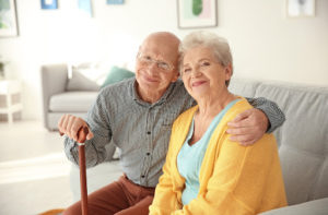 A senior couple smiling, sitting on a couch in their new independent living facility