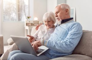 A senior couple using a laptop to research the different retirement community options available to find what best suits them