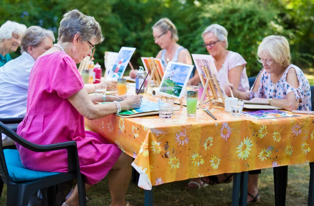 A group of seniors enjoying social connection during a painting class
