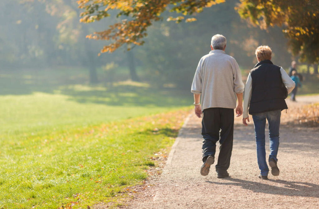 An elderly couple is walking in the park.