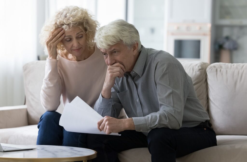 A stressed older couple at home reviews their finances.