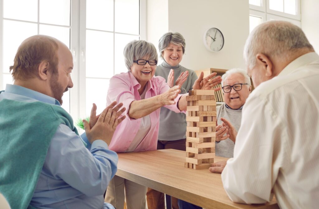 A group of seniors in a community laugh and play Jenga together.