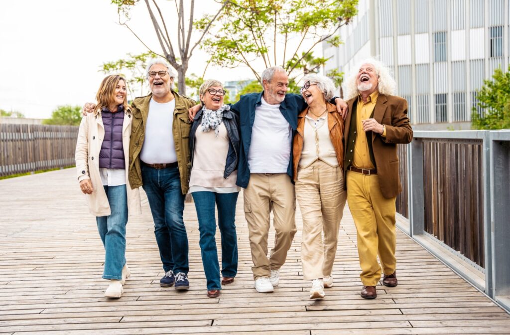 A group of older adults linking arms and laughing while out for a walk.