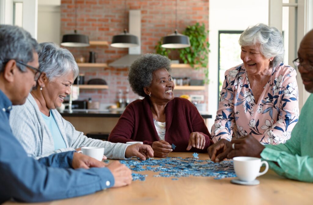 A group of senior friends sitting at a table together working on a puzzle at a senior living community