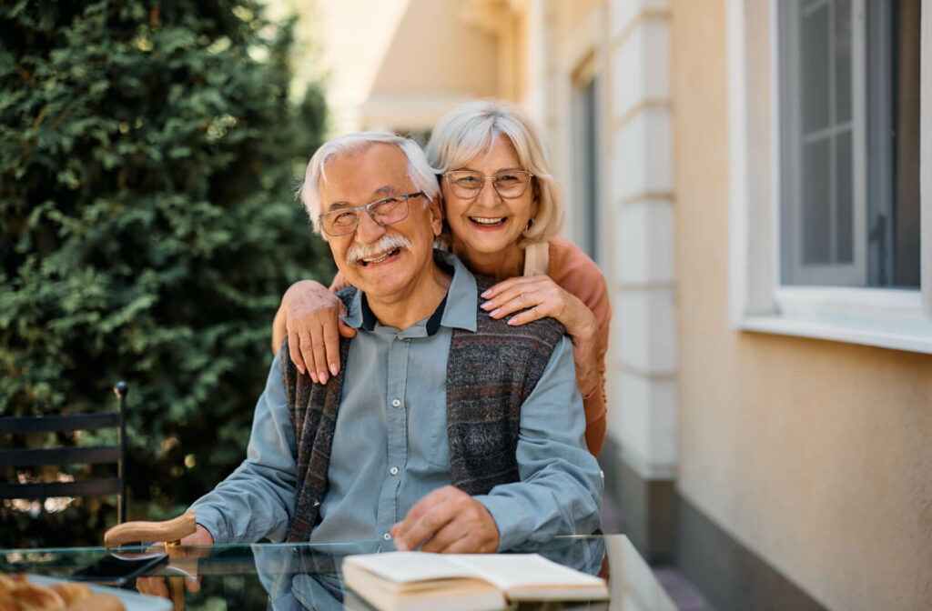 A senior couple smiles at the camera in senior living.